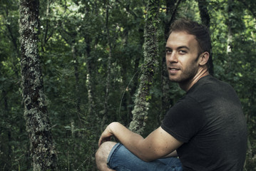 Portrait of an attractive man sitting in front of a leafy forest