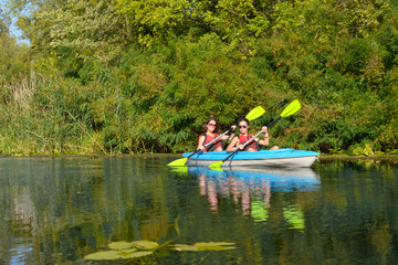 Fototapeta na wymiar Family kayaking, mother and daughter paddling in kayak on river canoe tour having fun, active autumn weekend and vacation with children, fitness concept 