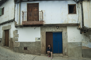Fototapeta na wymiar Young man sitting at the door of an old house in a village