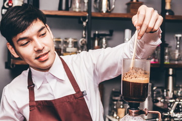 Handsome barista making coffee on syphon coffee maker in the cafe