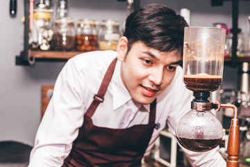Handsome barista making coffee on syphon coffee maker in the cafe