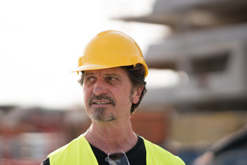 Portrait of a caucasian civil engineer wearing yellow reflective vest and hardhat looking away