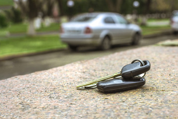 lost car keys on a marble slab, on a blurred car and park background