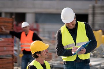 Civil engineer giving instructions to construction workers on construction site
