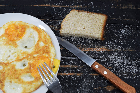 breakfast consisting of fried eggs with a slice of bread on a black table