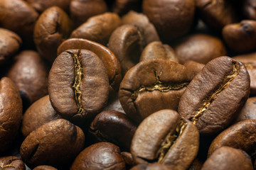 On the table lie roasted coffee beans, close-up.