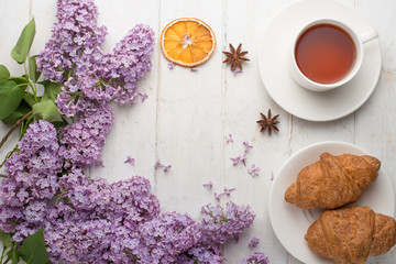 Lilac with croissants and tea on a light background with an empty space for the inscription.