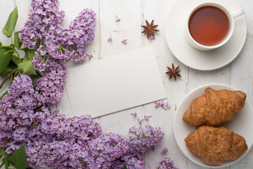 Lilac with croissants and tea on a light background with an empty space for the inscription.