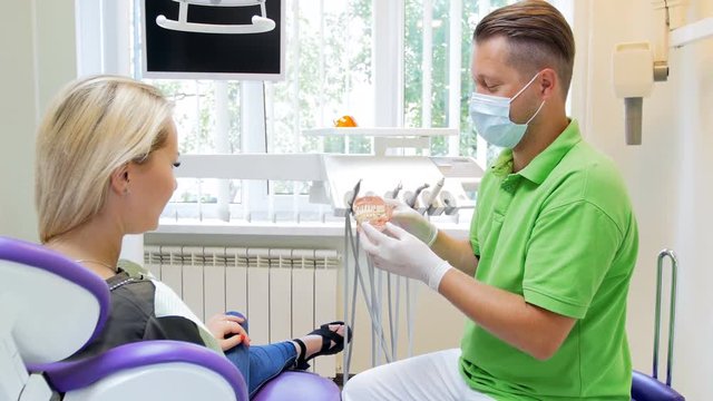 4k video of dentist showing teeth model to female patient