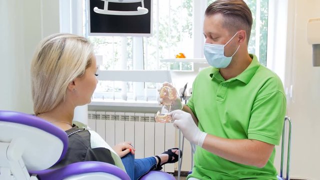 4k video of dentist explains teeth treatment to his patient on plastic jaw model