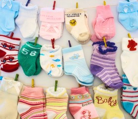 Baby socks and mittens hanging on lines with miniature clothes pegs