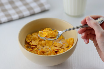 cornflakes with milk in a plate on a white table