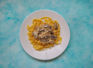 Pasta with mushrooms on a blue background. Copy space for your text.