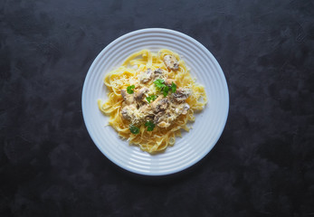 Pasta with mushrooms on a black background. Copy space for your text.