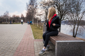 
girl, blonde, in a leather jacket walks on a summer park in the street