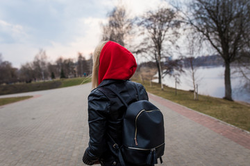 
girl, blonde, in a leather jacket walks on a summer park in the street