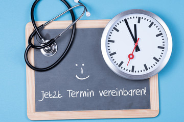 Uhr mit einem Stethoskop und dem Spruch jetzt Termin vereinbaren