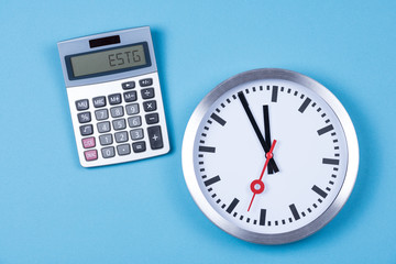 Taschenrechner mit dem Wort ESTG zur Einkommenssteuer und einer Uhr