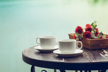 Cup of coffee on old wooden table with lake background