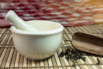 Mortar and dried herbs on bamboo mat