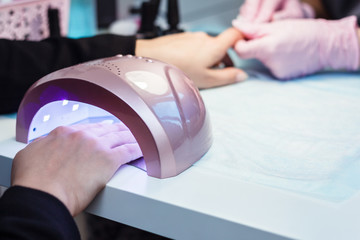 UV lamp gel for polishing manicure. The procedure in the beauty salon. The master covers the client's nails with varnish. - 203672148