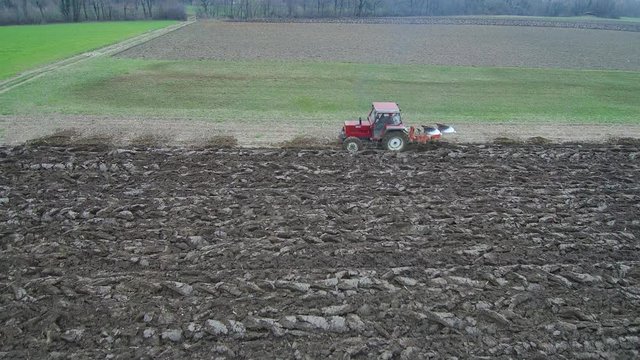 Agriculture and farming - Tractor plough a field in early spring aerial footage