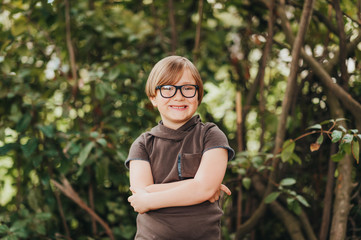 Strong, smart and funny little boy playing outdoors, wearing eyeglasses and dark swetshirt