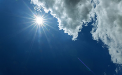 Bright sun on blue sky with clouds and sun