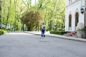 Woman using electric scooter in the park on a sunny day