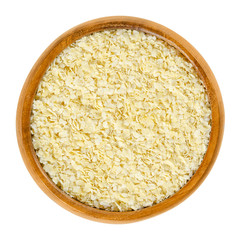 Millet flakes in wooden bowl. Light, yellow rolled millet, used for porridge, muesli and baking. Wheat and gluten free grain. Isolated macro food photo close up from above on white background.