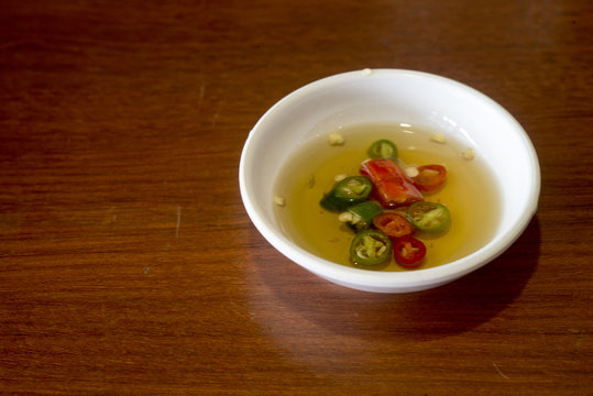 Pepper sauce in a white cup on a wooden table