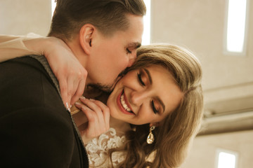 Fototapeta premium A young couple are basking, a man is kissing a girl. Emotions and smiles, enjoying the kiss.