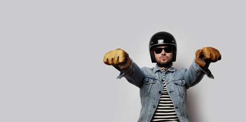 Young biker in a blue denim jacket pretending to ride a motorcycle isolated on white background....