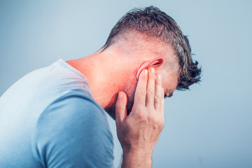 Fototapeta premium male having ear pain touching his painful head isolated on gray background