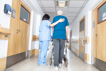 Asian nurse helping elder man walking in rehab facility