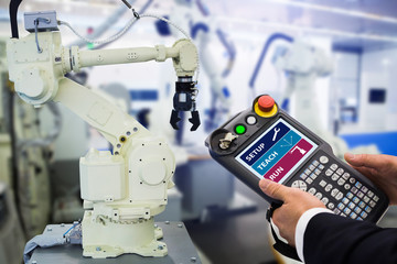 Engineer with teach pendant device. Programming robot with robotic arm. Smart factory 