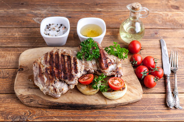 Grilled turkey fillet with spices, herbs and cherry tomatoes on a cutting board.