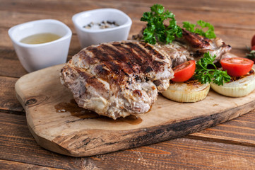Grilled turkey fillet with spices, herbs and cherry tomatoes on a cutting board.