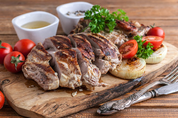 Grilled turkey fillet with spices, herbs and cherry tomatoes on a cutting board.