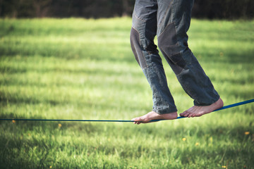 balancing exercise with slackline. Slacklining refers to the act of walking or balancing along a suspended length of flat webbing that is tensioned between two anchors.