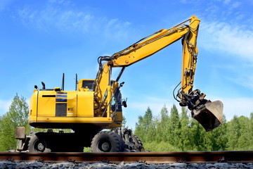Fototapeta na wymiar Rail excavator working with rubble. Excavators machine excavate on railway.