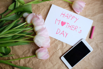 Bouquet of pink tulips with gift card and smartphone on brown crumpled paper background, Happy mother's day and valentine day