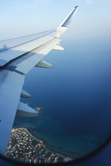 Traveling by plane. View from the window to the sea and blue sky.