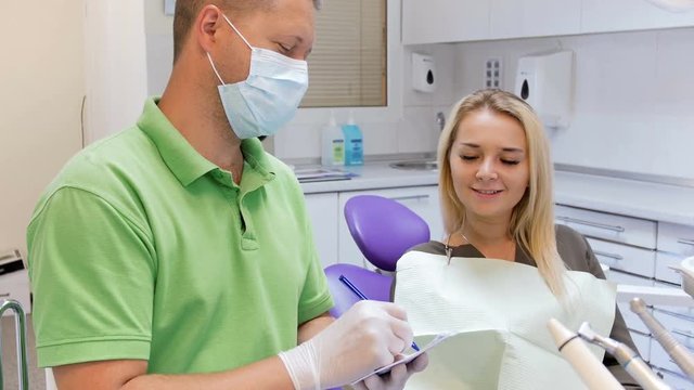 4k video of male dentist writing prescription on paper for his patient