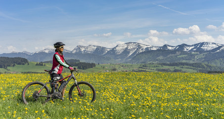Fototapeta na wymiar Seniorin mit dem Mountainbike im Bergfrühling im Allgäu, bayern,Deutschland