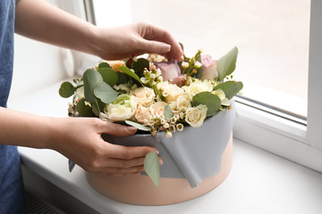 Female florist holding box with flowers indoors