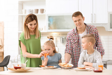 Parents and cute little children having breakfast with tasty toasted bread at table in kitchen