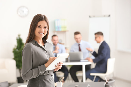Young smiling businesswoman with tablet computer in conference room