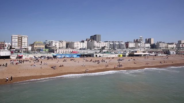 Brighton beach busy with people in fine weather East Sussex UK pan