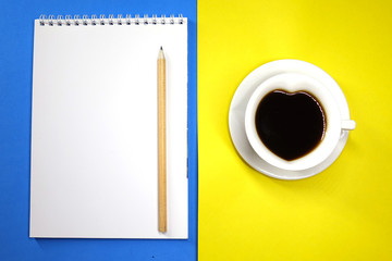 Notepad and coffee on colored background top view